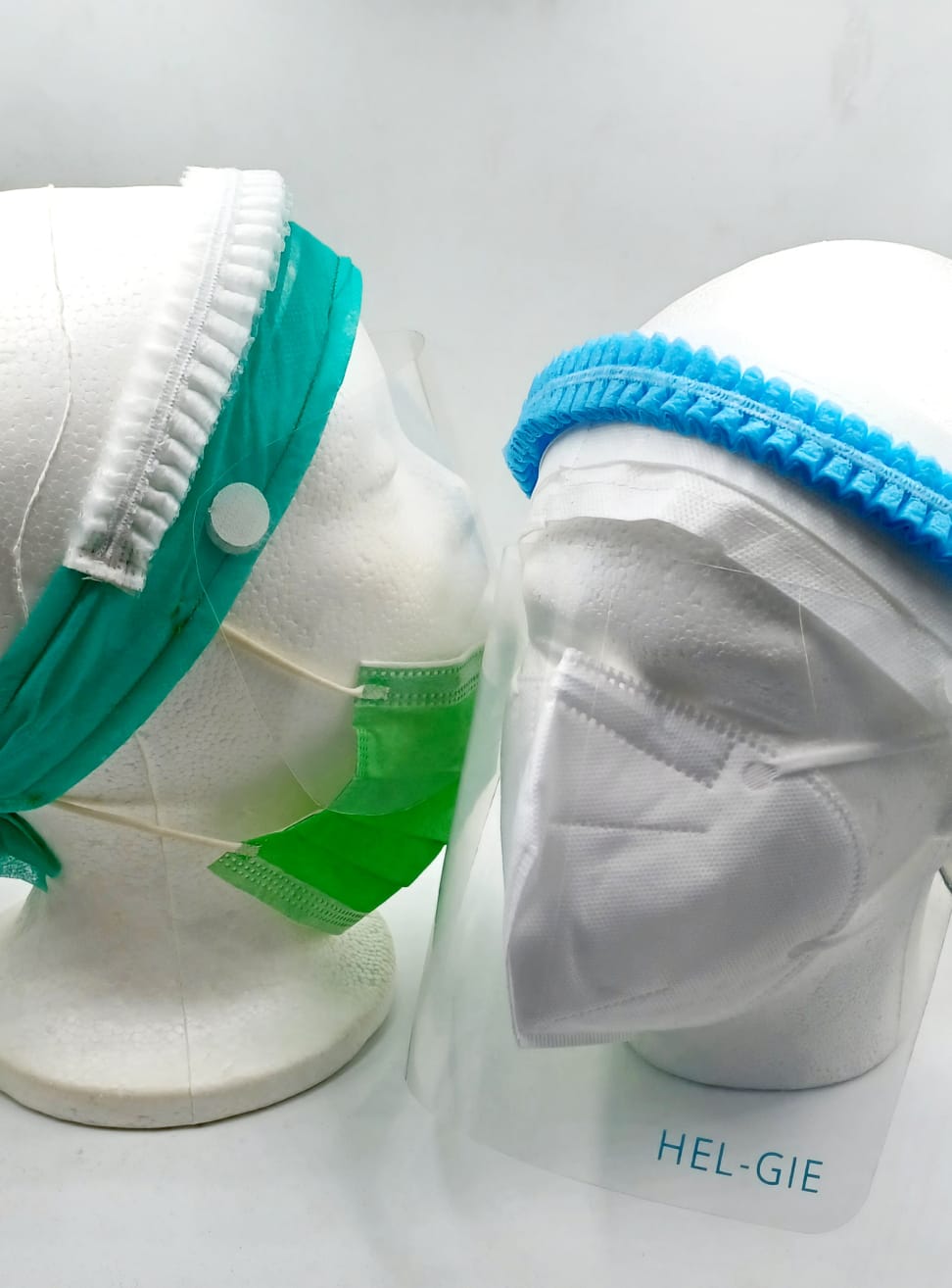 Two display heads wearing the HG Mask, each combining a face mask, removable face shield, and headgear in a single unit.
